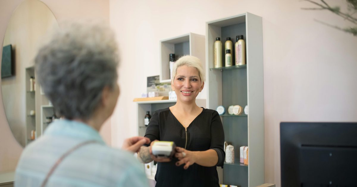 Profissional de receção num cabeleireiro em Portugal a atender uma cliente no balcão